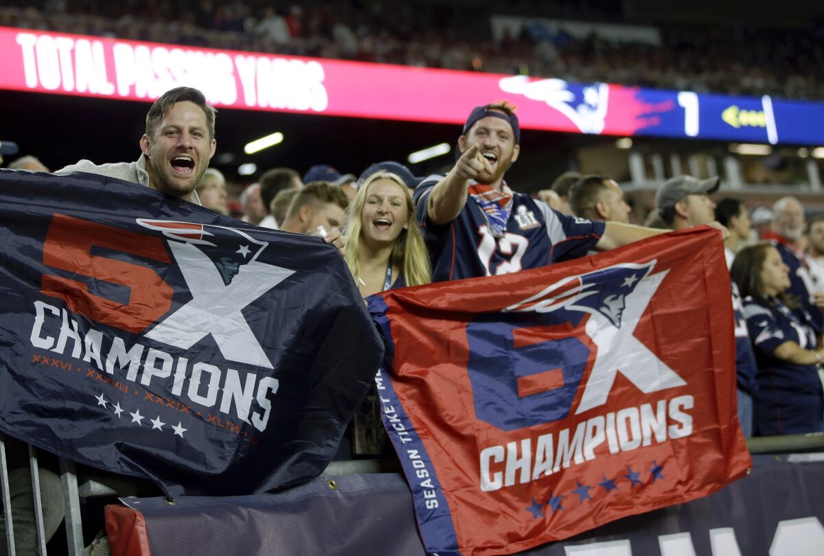 New England Patriots fans hold banners commemorating two of the team's Super Bowl victories 