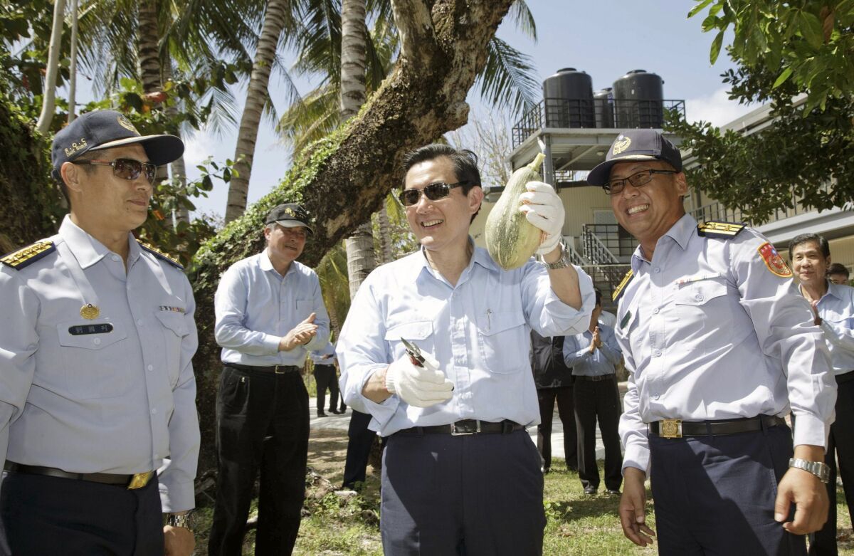 In this photo released by the Taiwan Presidential Office, Taiwan President Ma Ying-jeou displays a locally grown fruit during his visit to Taiping Island on Thursday.