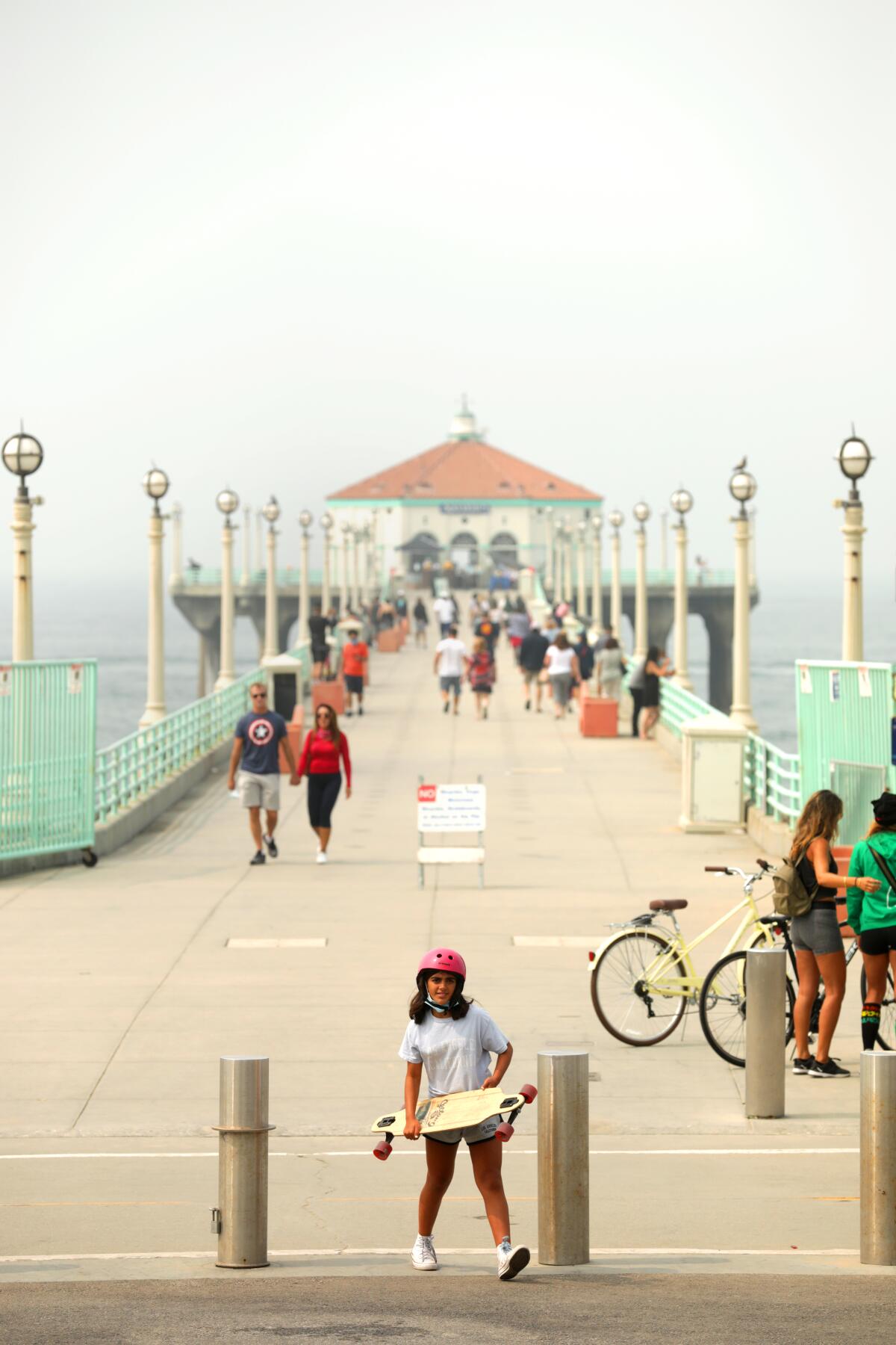 Cyclists, walkers and a skateboarder enjoy the Manhattan Beach Pier. 
