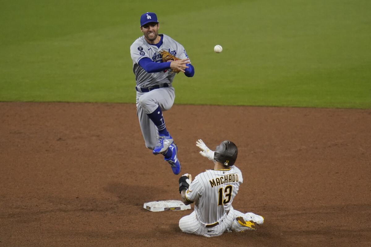 Dodgers second baseman Chris Taylor turns a double play in front of Padres baserunner Manny Machado.