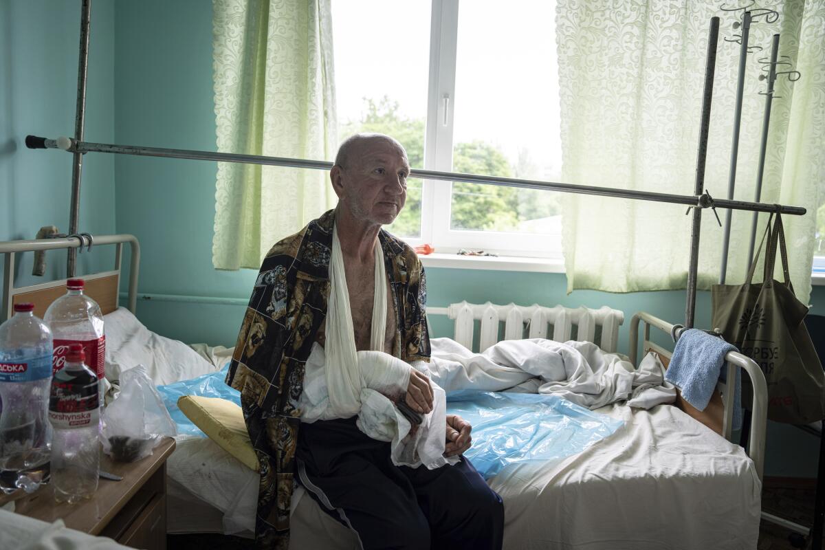 A 60-year-old man with a bandaged arm sits on a bed in a hospital in Ukraine.