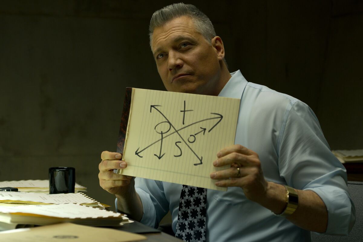 A man holds up a piece of cardboard with arrows drawn on it
