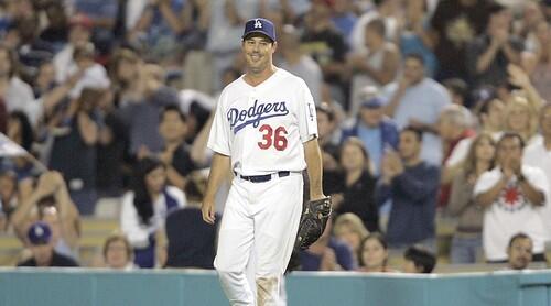Starting pitcher Greg Maddux smiles and fans cheer after he beat out the runner to cover first base.