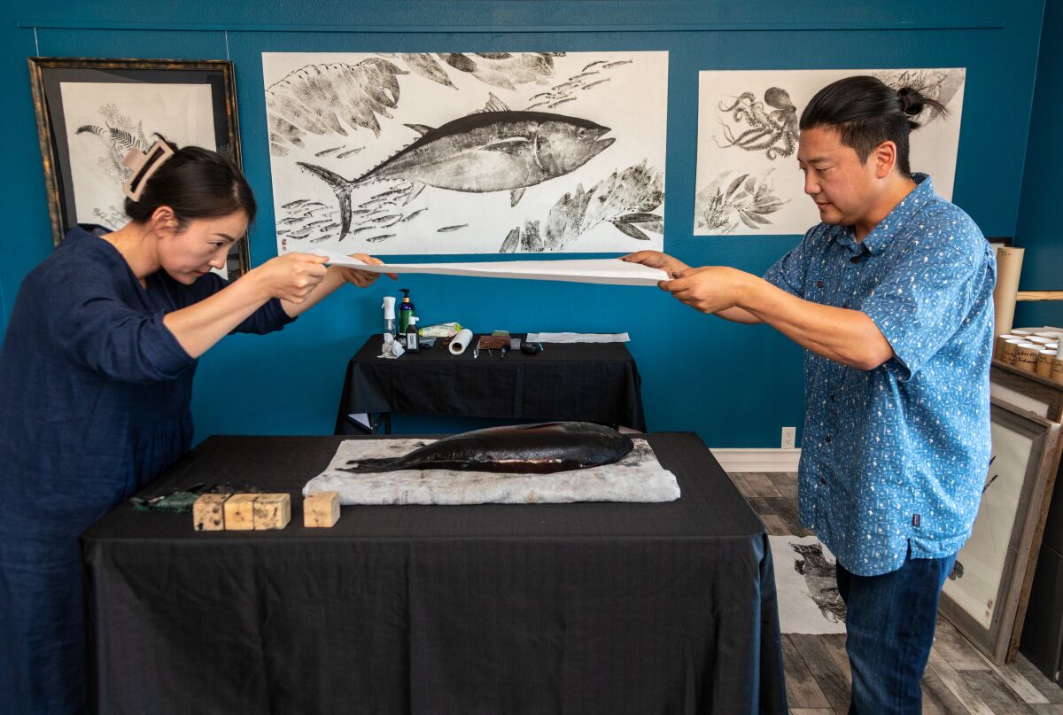 Two people making art using a fish.