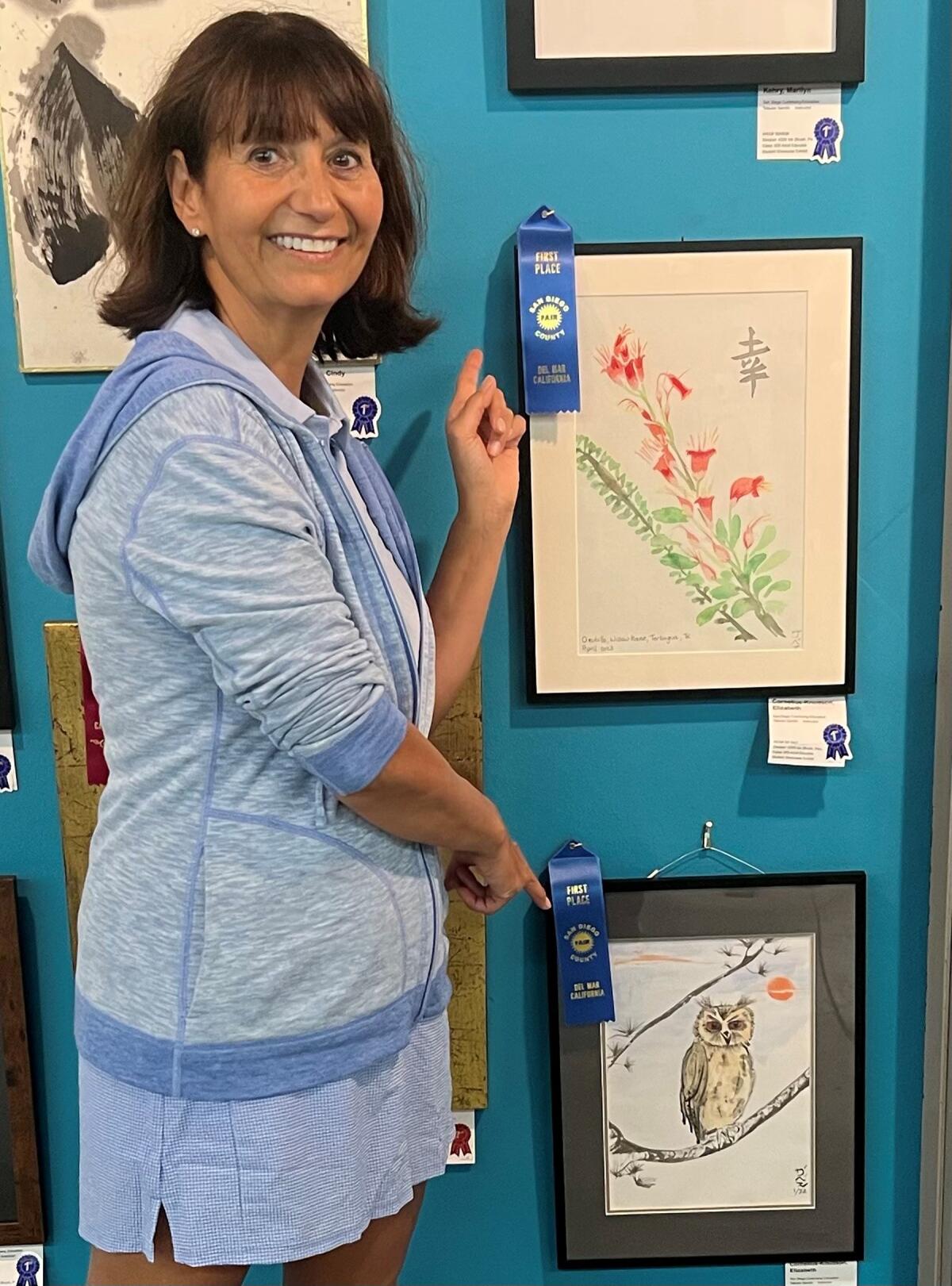 PB resident Zabeth Cornelius-Knudsen with her two paintings that won first-place awards at the 2023 San Diego County Fair.