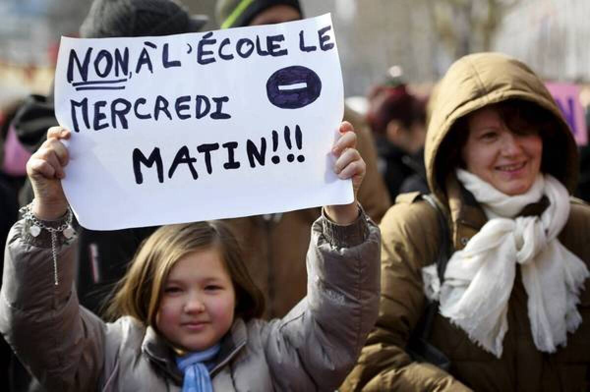 A girl holds a sign reading, "No to school on Wednesday morning" during a demonstration in front of city hall in Paris.