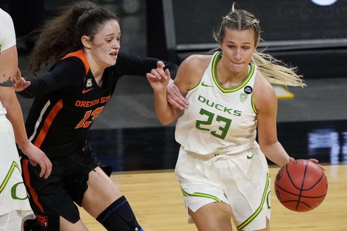 Oregon's Maddie Scherr (23) drives around Oregon State's Sasha Goforth (13) during the first half of an NCAA college basketball game in the second round of the Pac-12 women's tournament Thursday, March 4, 2021, in Las Vegas. (AP Photo/John Locher)