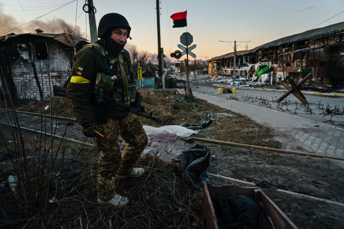 A Ukrainian soldier stands near the bodies of Russian troops.