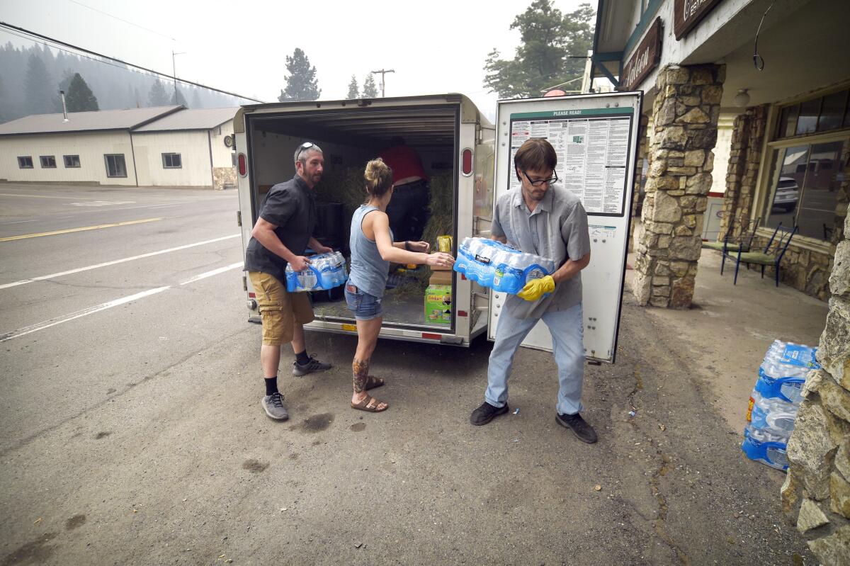 Three people unload donated supplies from a trailer.