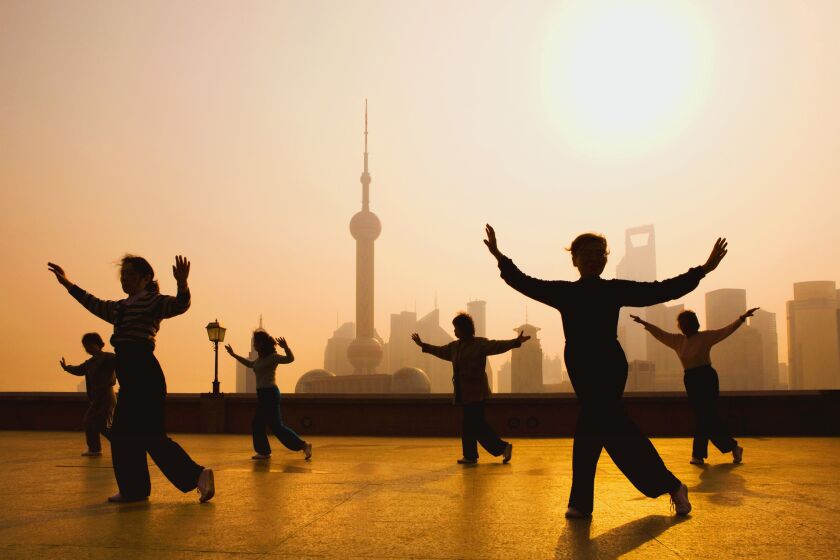 People gather to practice movements on the Bund, with the Shanghai skyline in the background.