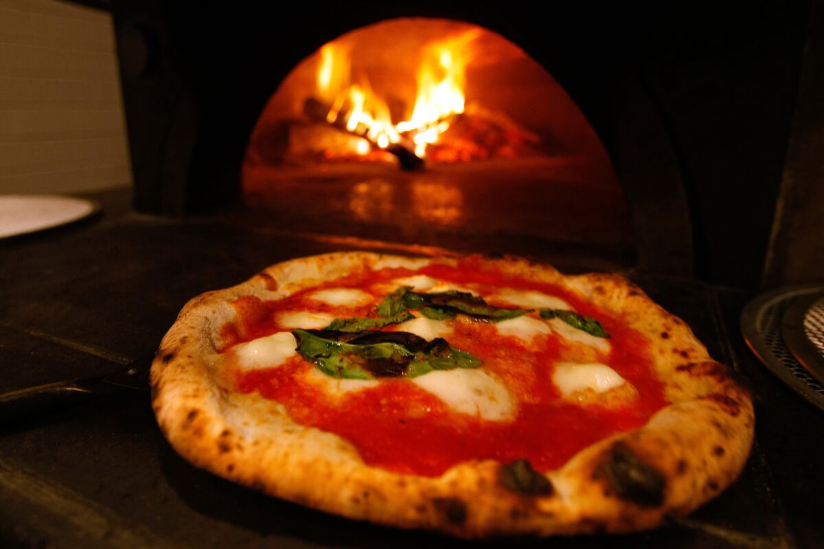 A Margherita pizza with San Marzano tomatoes, buffalo mozzarella and aged Parmigiano-Reggiano comes out of the 850-degree oven at Mother Dough in Los Feliz.