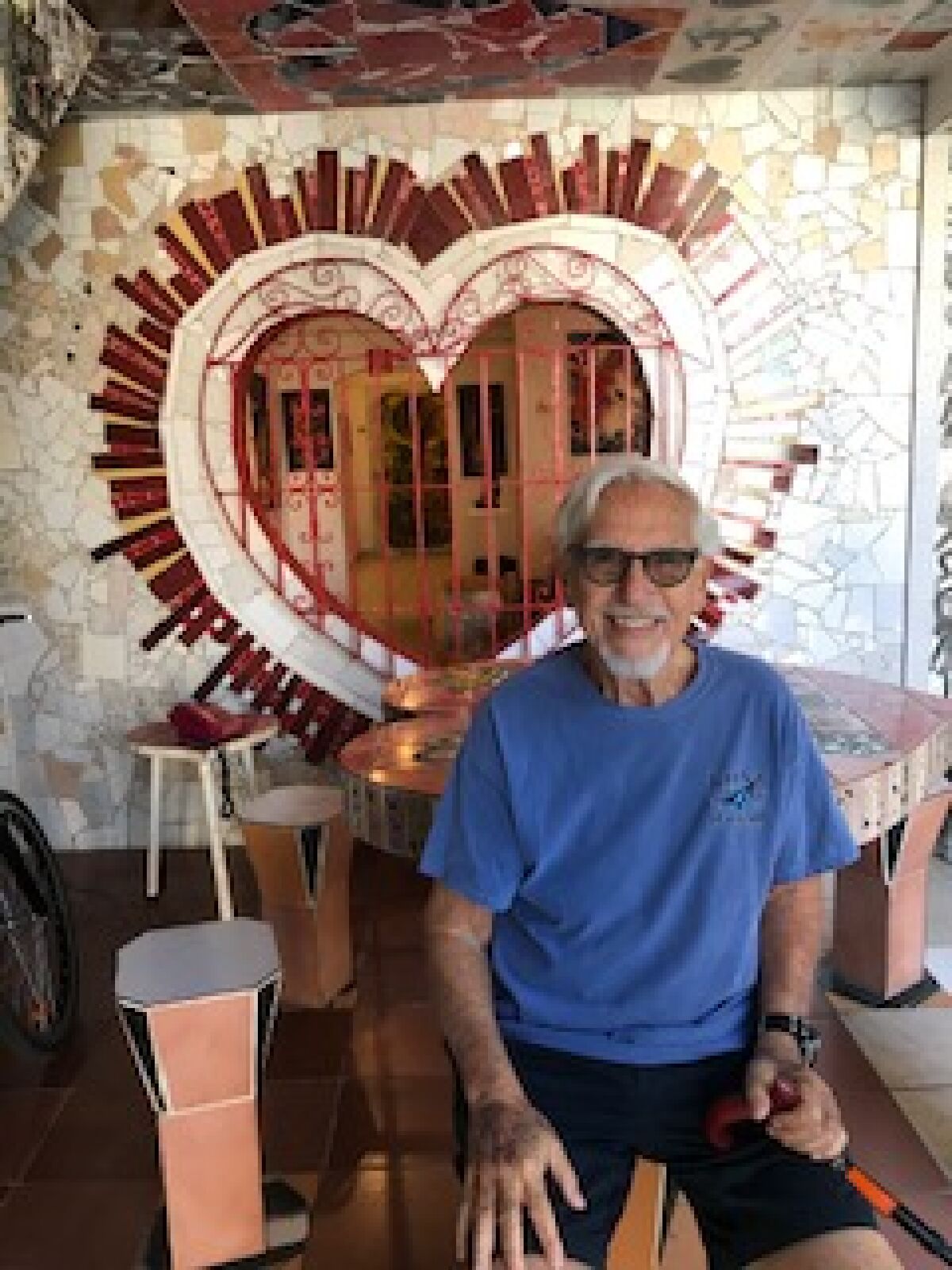 Allen Freehling wears a blue T-shirt in front of a heart-shaped mirror in Havana.