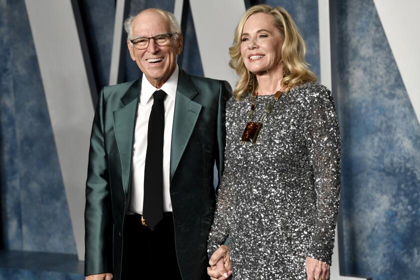 Jimmy Buffett, left, and his wife Jane Slagsvol hold hands at and smile at an Oscars party