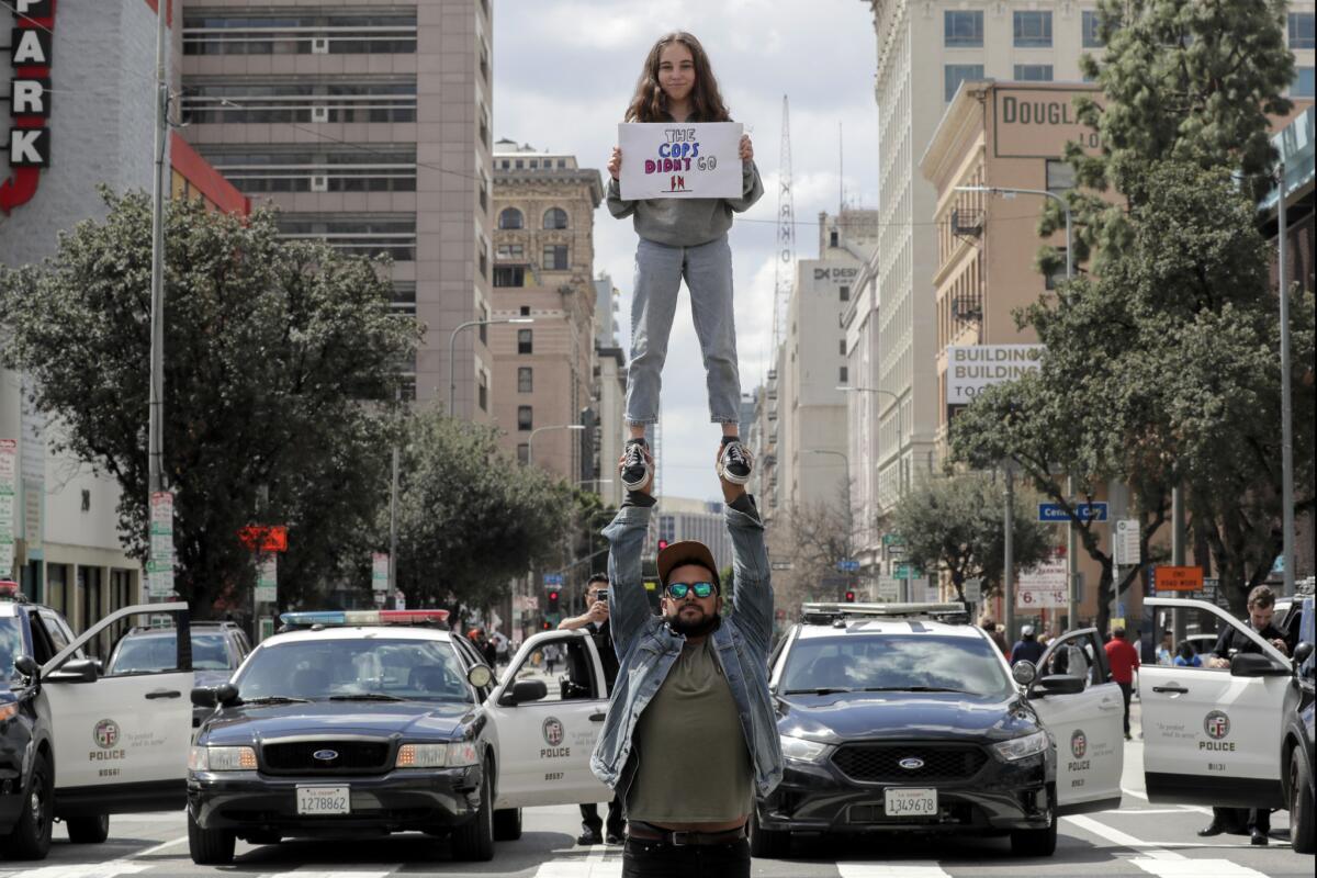 LOS ANGELES: Emie Malanaphy, 13, lifted by Jonathan Rea, 29, holds a sign alluding the Florida sheriff's deputy who didn't go in to confront the gunmen during the Parkland, Fla. shooting.