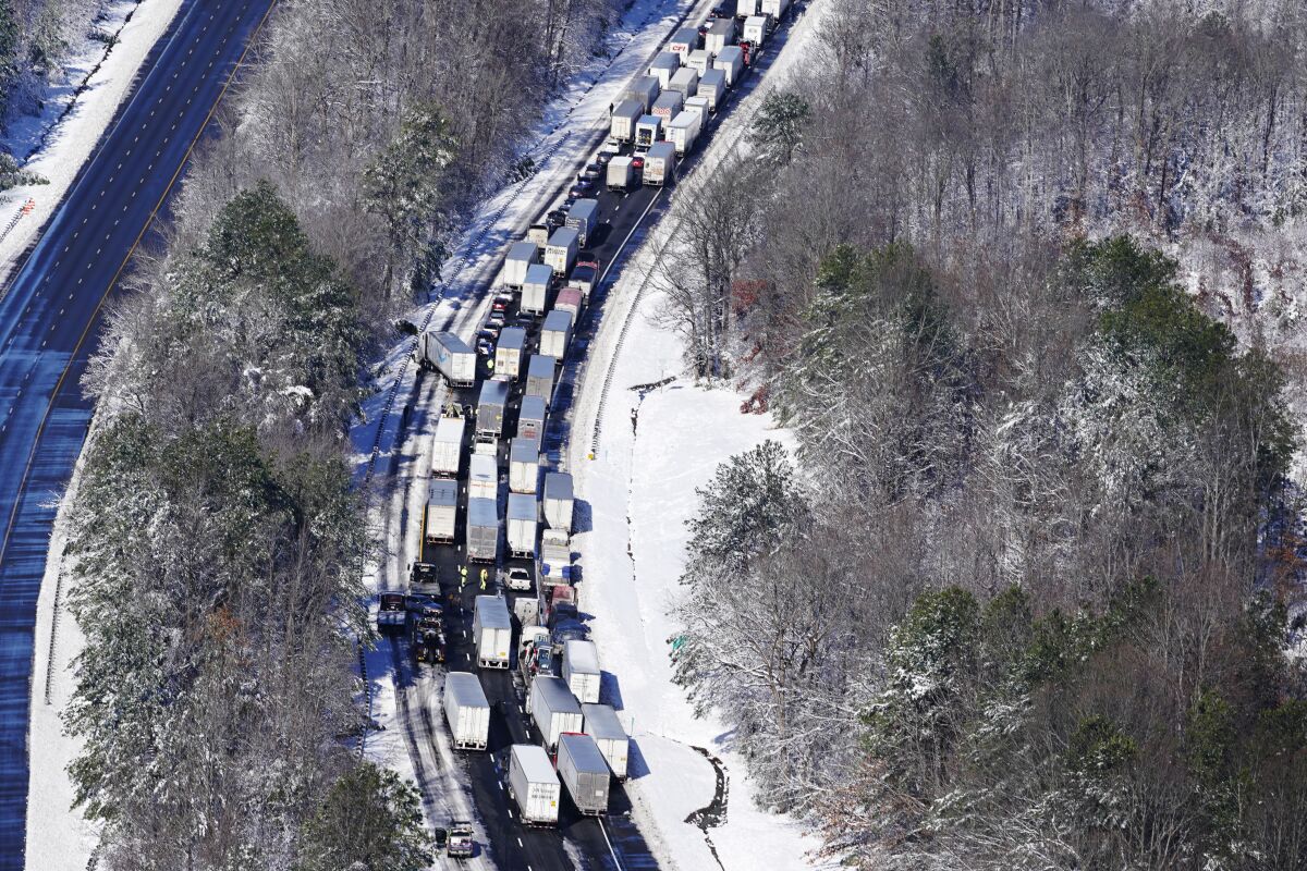Trucks and cars stuck bumper to bumper on a highway in a snowy area 