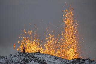 Scientist from the University of Iceland take measurements and samples standing on the ridge in front of the active part of the eruptive fissure of an active volcano in Grindavik on Iceland's Reykjanes Peninsula, Tuesday, Dec. 19, 2023. (AP Photo/Marco Di Marco)