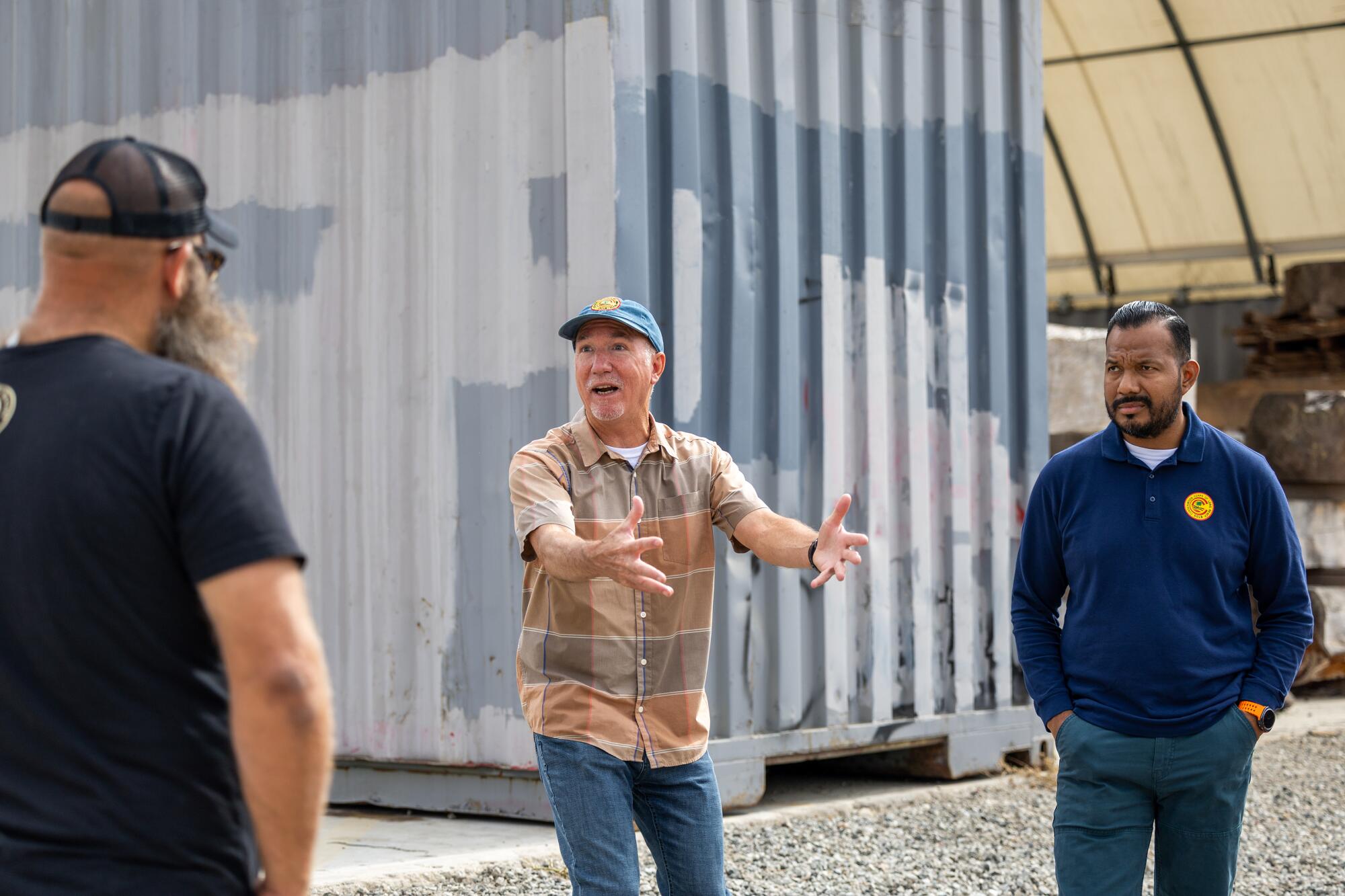 Three men talk at Long Beach lumber yard.