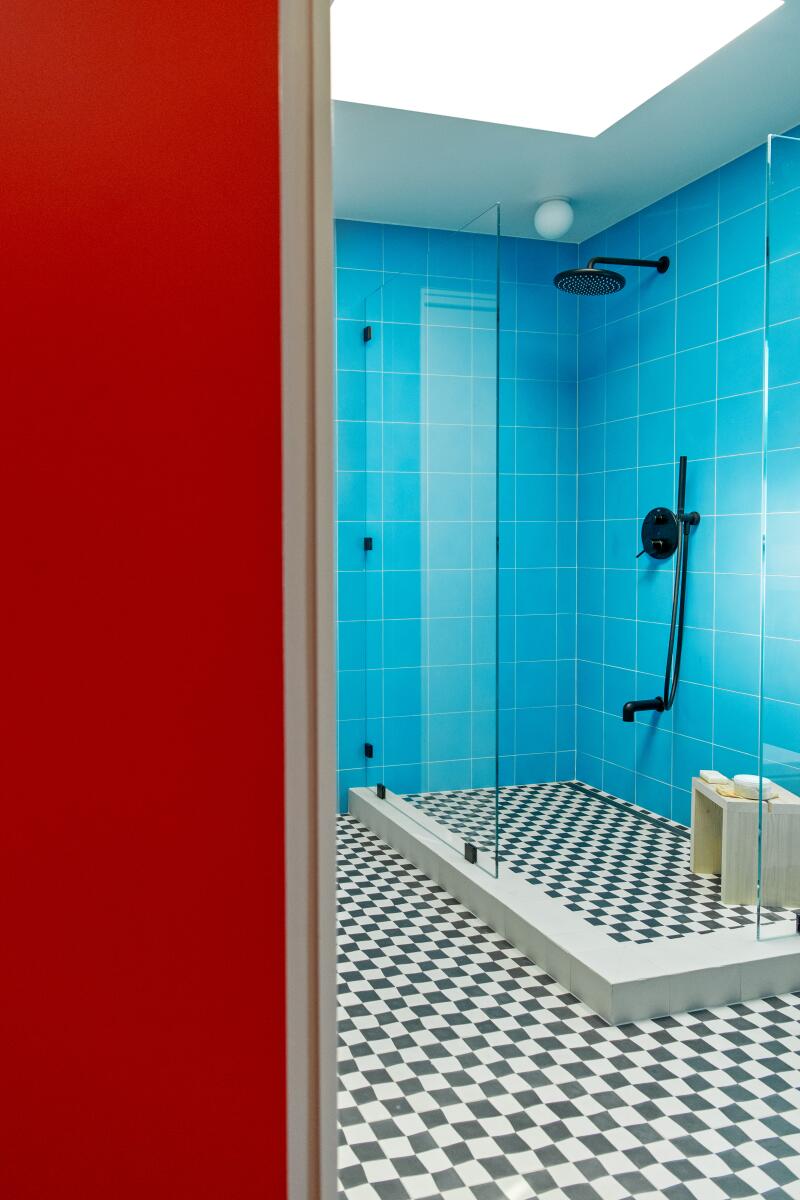 A shower with bright blue tile and black and white tile flooring