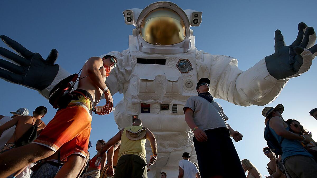 Festivalgoers walk beneath a large inflatable astronaut at Coachella's 2014 edition.