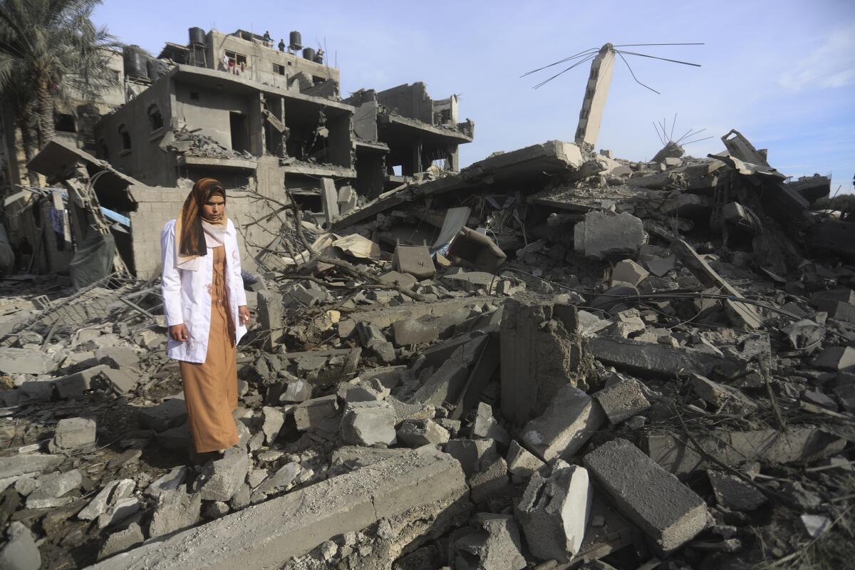 A Palestinian woman walks past structures destroyed by Israeli bombardment in Rafah.
