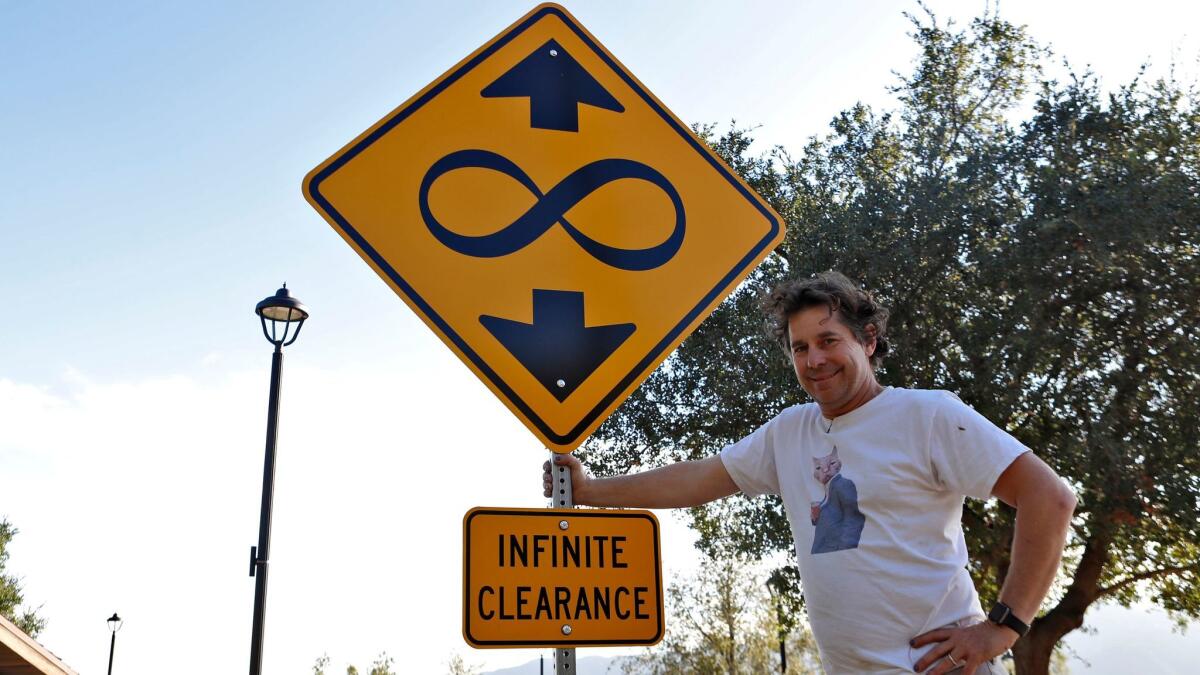 Artist Scott Froschauer stands next to his "Infinite Clearance" street sign artwork at Deukmejian Wilderness Park in Glendale, on Tuesday.