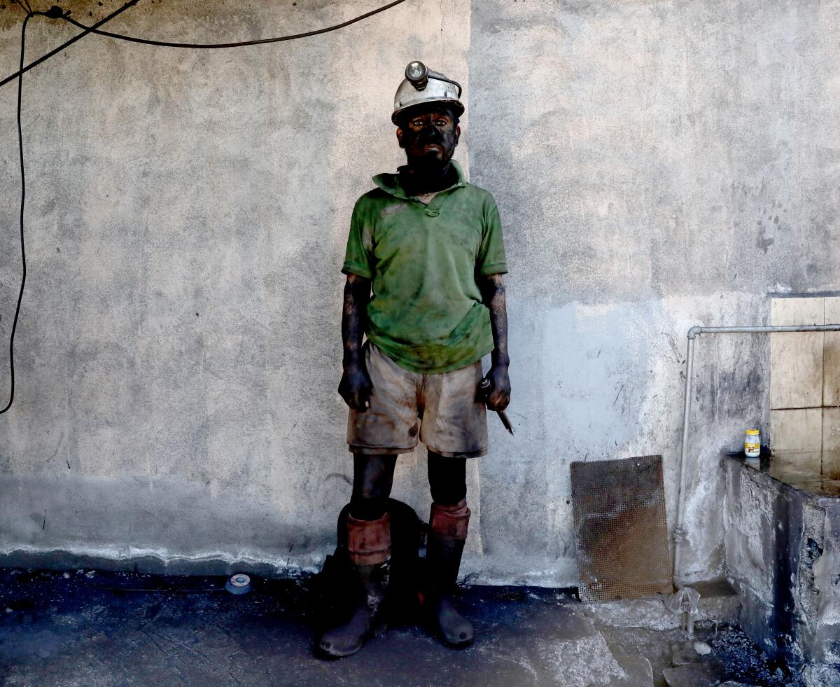 A coal miner with face, arms and legs covered in soot