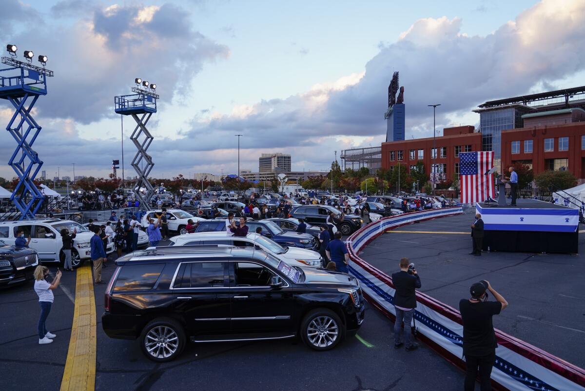 People watch former President Obama from beside or inside their cars at Citizens Bank Park's car lot.