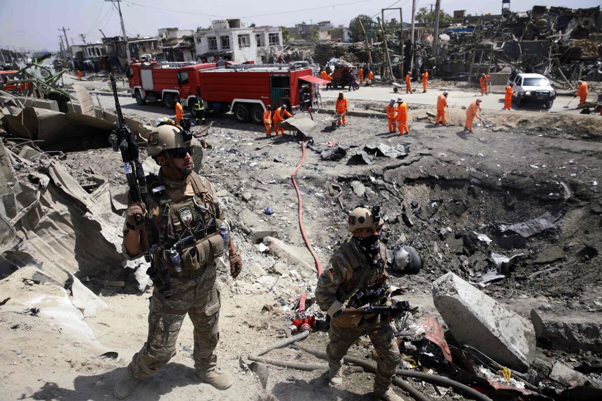 Afghan security forces pass near a crater from a Taliban bombing in Kabul on Sept. 3. 