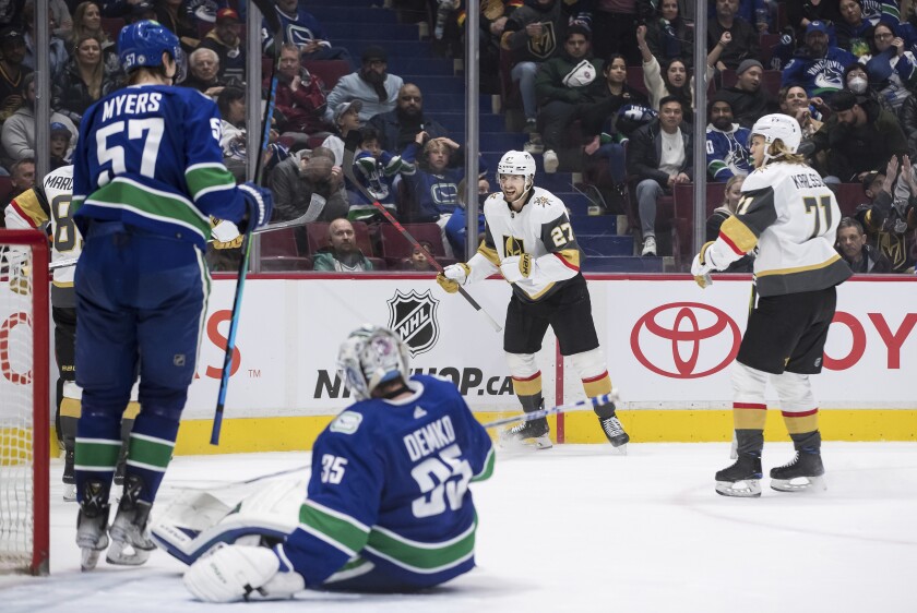 Vegas Golden Knights' Shea Theodore (27) and William Karlsson (71) celebrate after Theodore scored against Vancouver Canucks goalie Thatcher Demko (35) during overtime in an NHL hockey game Sunday, April 3, 2022, in Vancouver, British Columbia. (Darryl Dyck/The Canadian Press via AP)