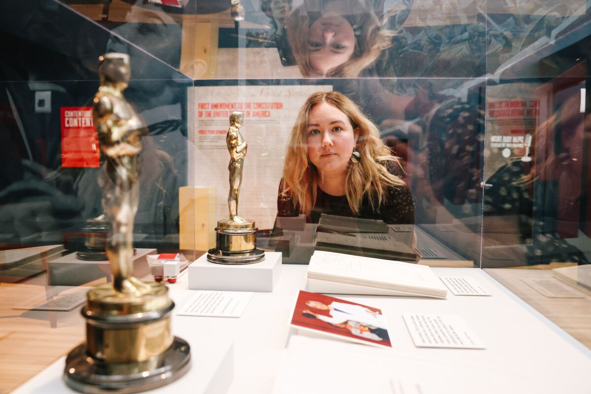 La conservatrice de Skirball, Cate Thurston, regarde à travers une vitrine contenant deux Oscars et d’autres objets