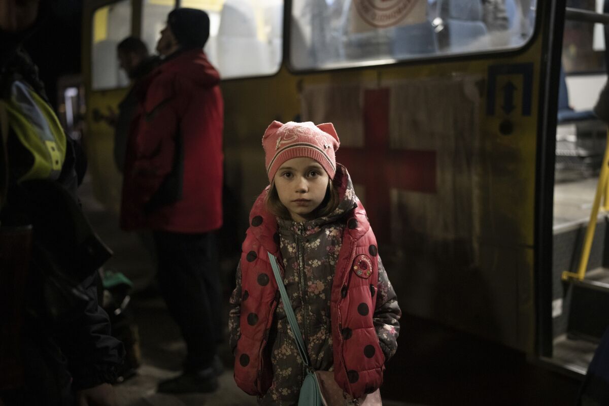 An internally displaced girl waits for family members outside the bus as they arrive in Zaporizhzhia, Ukraine, Friday, April 1, 2022. (AP Photo/Felipe Dana)