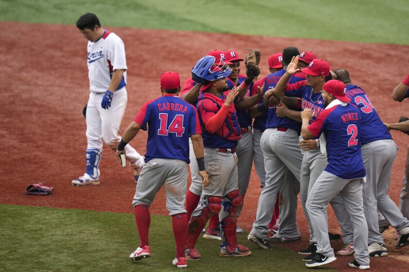 South Korea's Hyunsoo Kim, left, leaves the field as the Dominican Republic players celebrate the team's 10-6 win in the bronze medal baseball game at the 2020 Summer Olympics, Saturday, Aug. 7, 2021, in Yokohama, Japan. (AP Photo/Jae C. Hong)