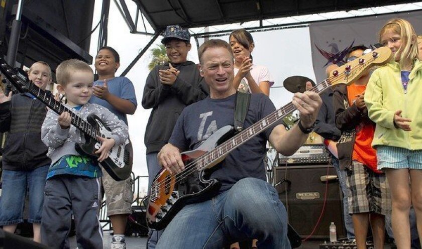 Gary Sinise with his Lt. Dan Band shows off his bass playing to Andrew James Bretzman, 3, after inviting children onto the stage.