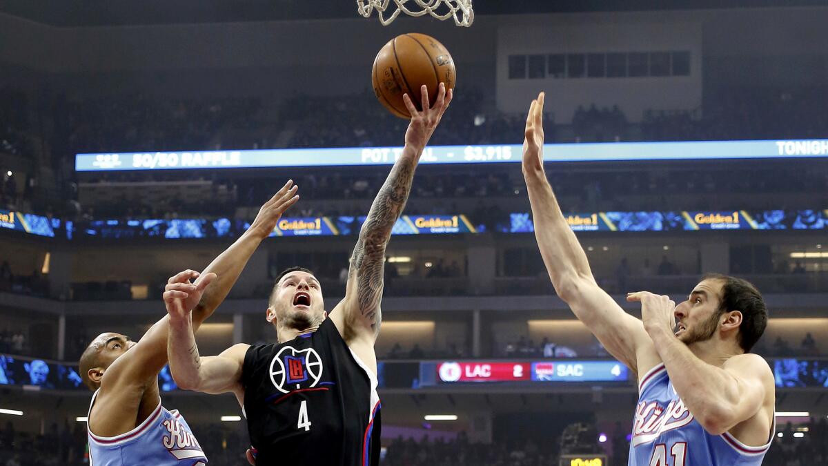 Clippers guard J.J. Redick (4) drives to the basket between Kings guard Arron Afflalo, left, and center Kosta Koufos during the first half.