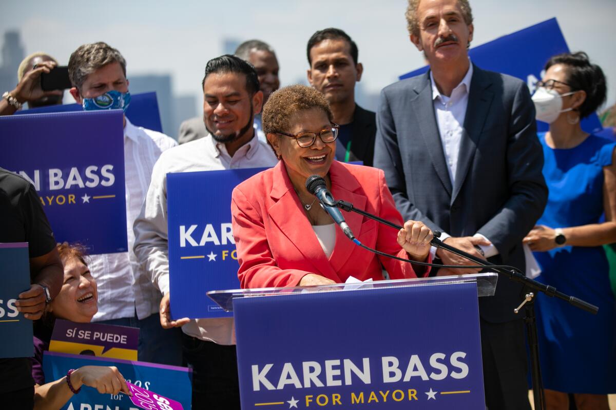 Karen Bass stands at a podium and speaks into a microphone
