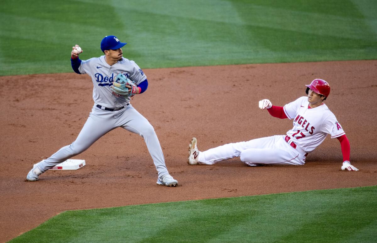 Dodgers second baseman Miguel Vargas looks to first as Angels pitcher Shohei Ohtani is out while sliding into second base.