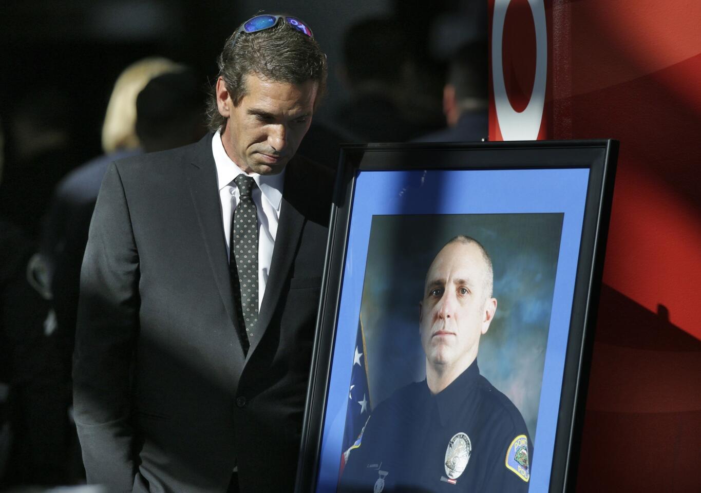 Christopher Diamond, 47, pauses by the photo of his younger brother, Pomona SWAT Officer Shaun Diamond, at the funeral held at Citizens Business Bank Arena in Ontario.