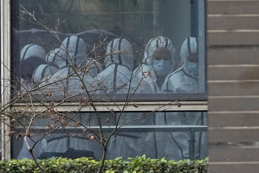 FILE - Members of a World Health Organization team are seen through a window wearing protective gear during a field visit to the Hubei Animal Disease Control and Prevention Center for another day of field visit in Wuhan in central China's Hubei province, on Feb. 2, 2021. Nearly two years into the COVID-19 pandemic, the origin of the virus tormenting the world remains shrouded in mystery. (AP Photo/Ng Han Guan, File)