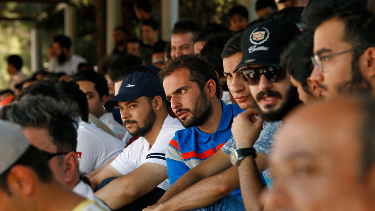 Drivers and spectators are predominantly male at a racetrack in Tehran.