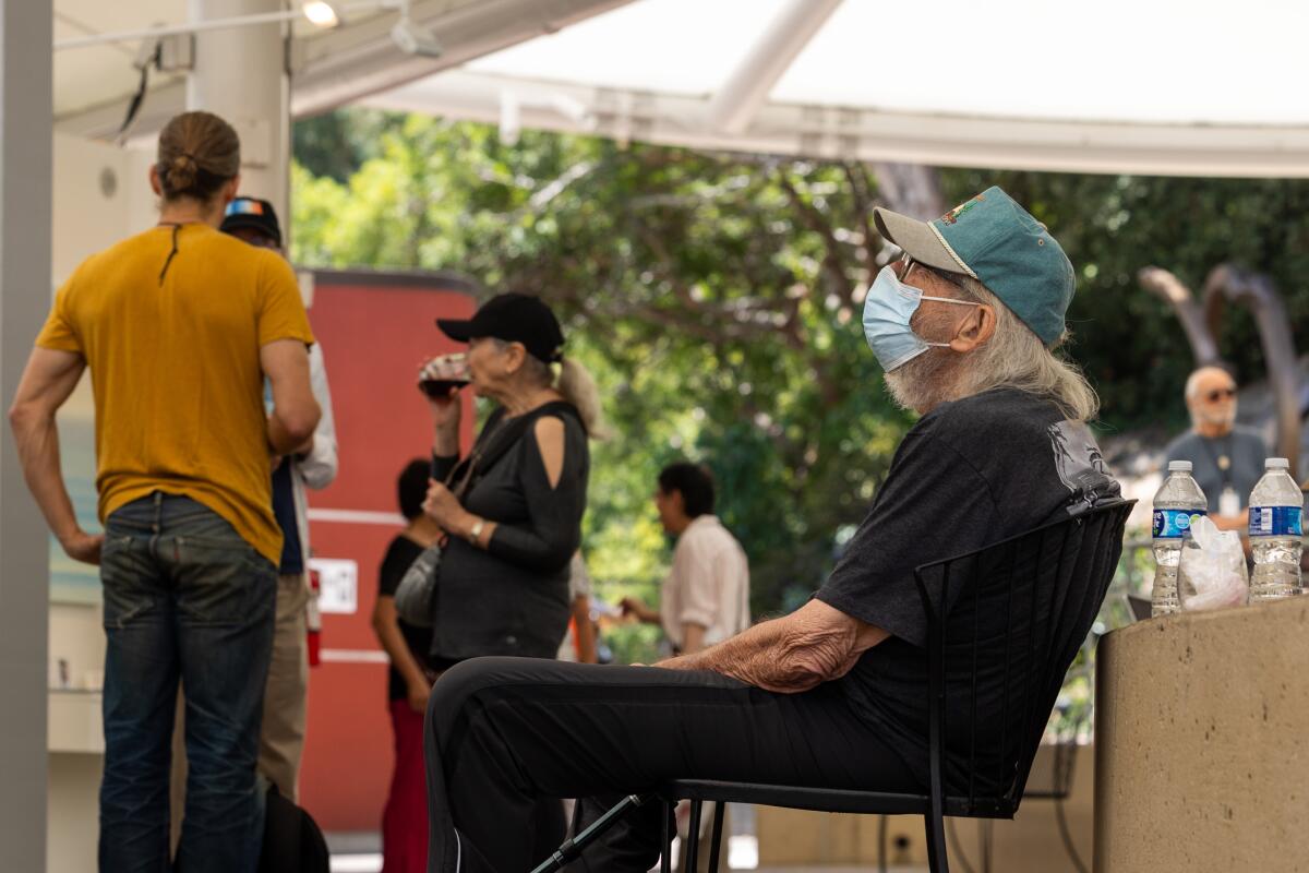 An individual sits with a mask on at the Festival of Arts in Laguna Beach.
