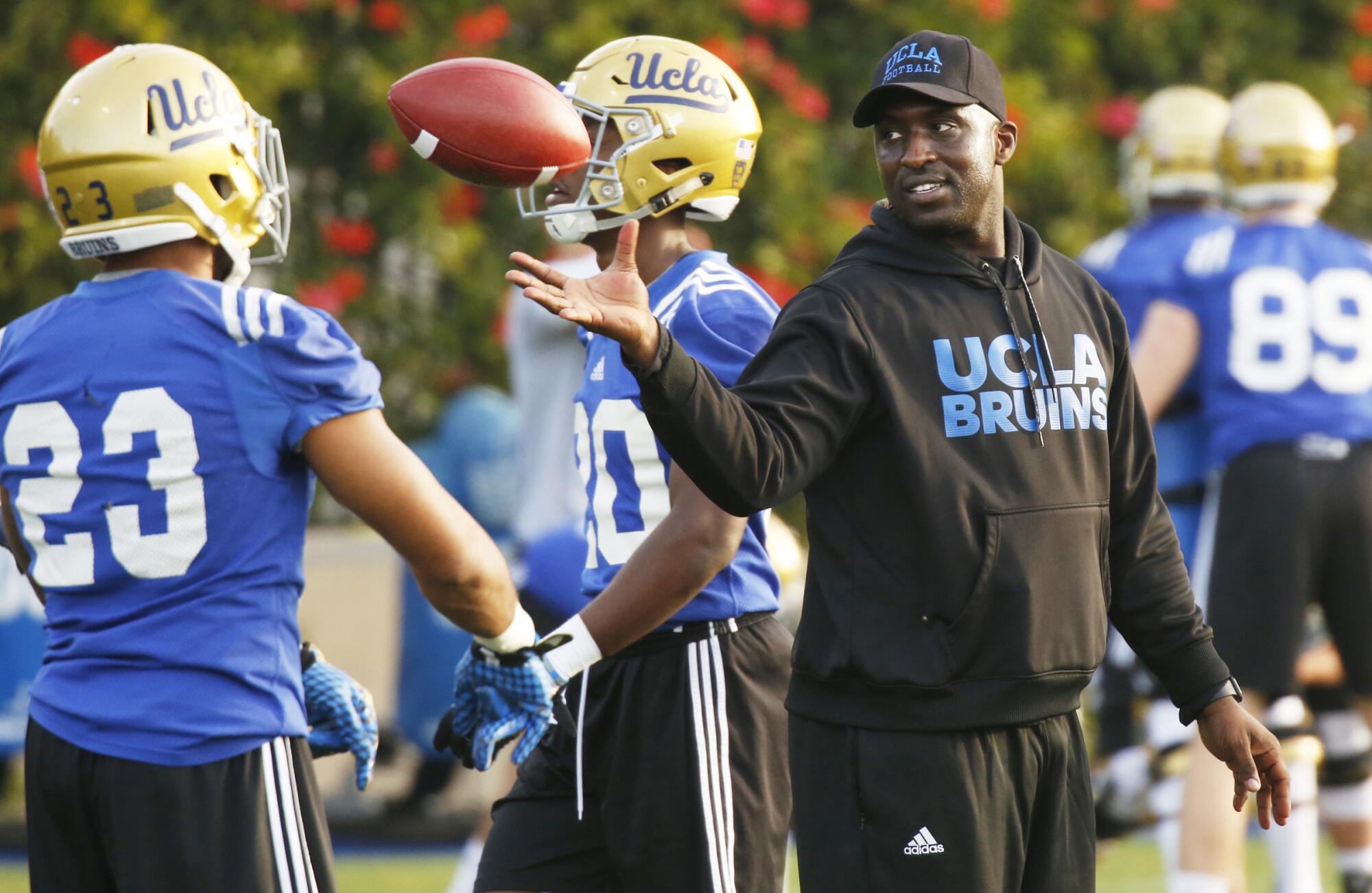 UCLA football's DeShaun Foster works with running backs.