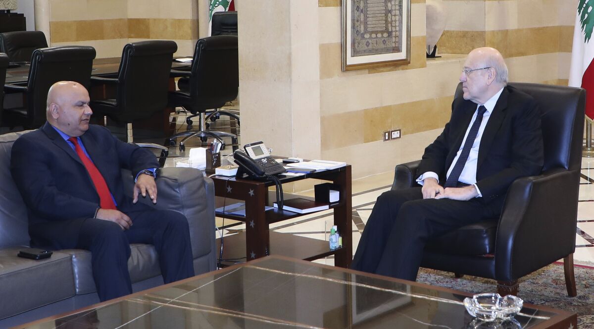 In this photo released by Lebanon's official government photographer Dalati Nohra, Lebanese Prime Minister Najib Mikati, right, meets with World Bank Regional Director Saroj Kumar Jha, at the government palace, in Beirut, Lebanon, Thursday, April 7, 2022. Lebanon and the International Monetary Fund reached a tentative agreement on comprehensive policies Thursday that could eventually pave the way for unlocking billions of dollars in loans to the crisis-hit country.(Dalati Nohra via AP)