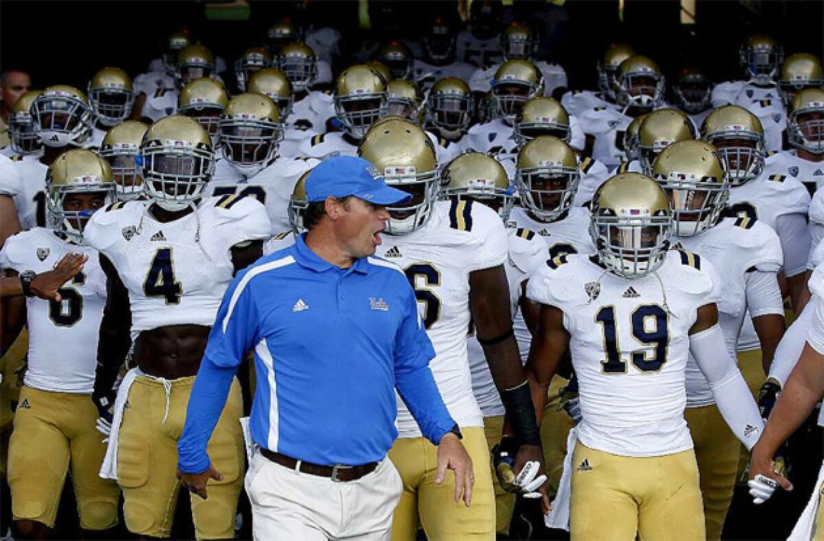 Coach Jim Mora leads the UCLA Bruins to the field to take on the Rice Owls last August.
