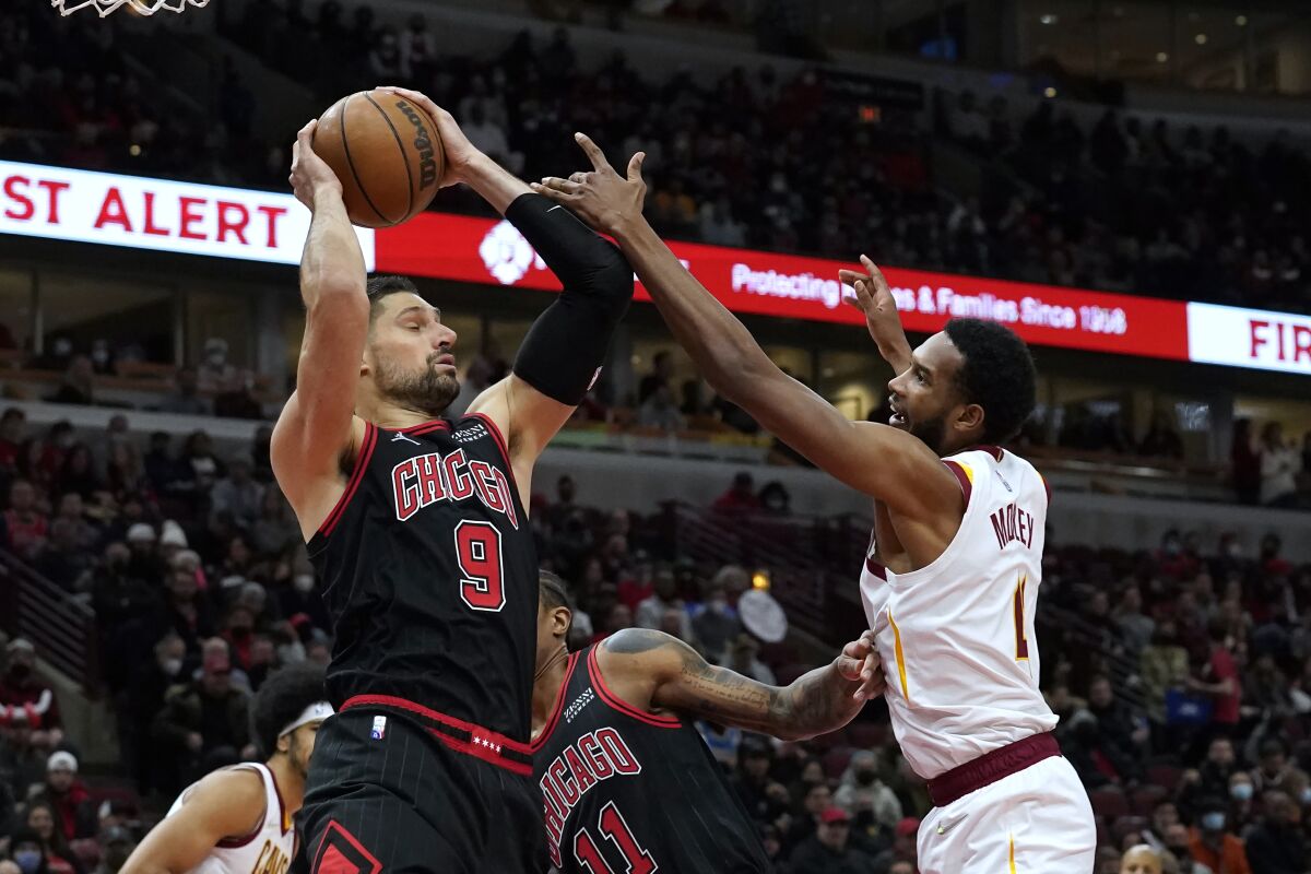 Chicago Bulls' Nikola Vucevic (9) grabs a defensive rebound as Cleveland Cavaliers' Evan Mobley defends during the first half of an NBA basketball game Wednesday, Jan. 19, 2022, in Chicago. (AP Photo/Charles Rex Arbogast)