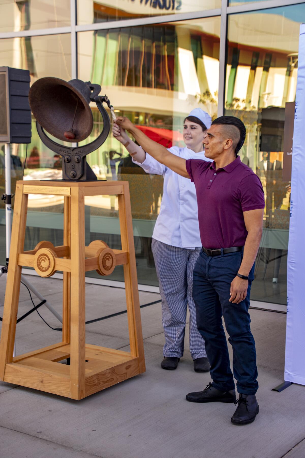 Nutrition and dietetics student Bonifacio Arrieta Cortes and culinary arts student Lindsay Taeger ring the dedication bell.