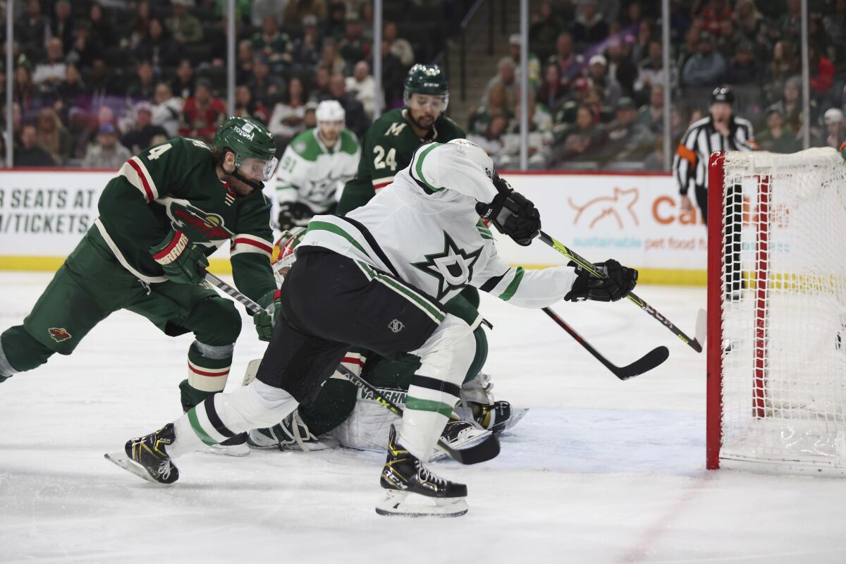 Dallas Stars left wing Jason Robertson (21) scores a goal against Minnesota Wild goaltender Kaapo Kahkonen (partially obscured) during the second period of an NHL hockey game Sunday, March 6, 2022, in St. Paul, Minn. (AP Photo/Stacy Bengs)