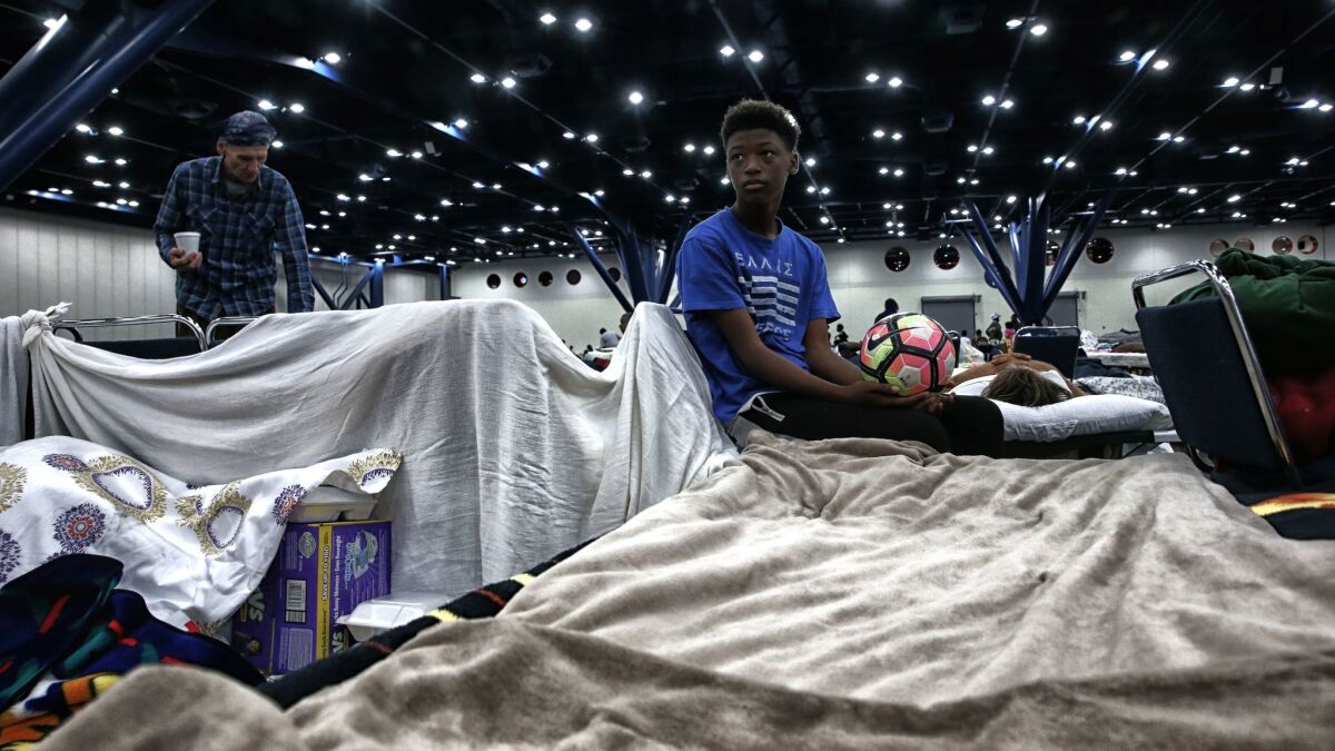 Travis Smith, 14, rests on a cot where his family sleeps at the George R. Brown Convention Center, where thousands of Hurricane Harvey evacuees are housed.