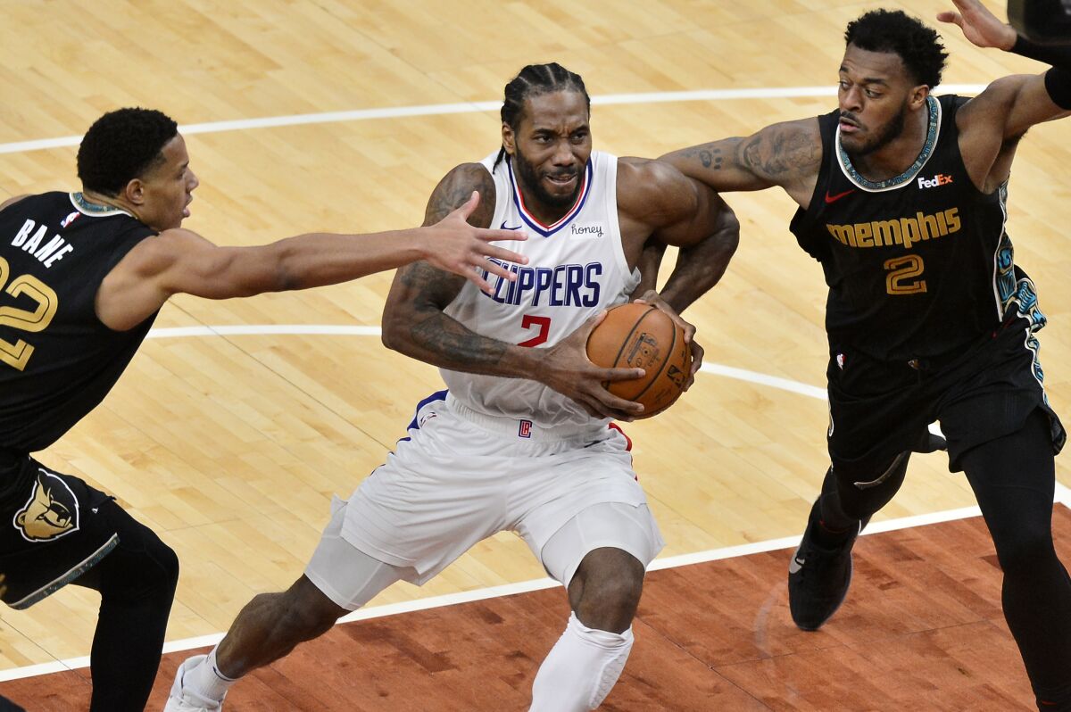 Clippers forward Kawhi Leonard drives by Memphis Grizzlies guard Desmond Bane and center Xavier Tillman.