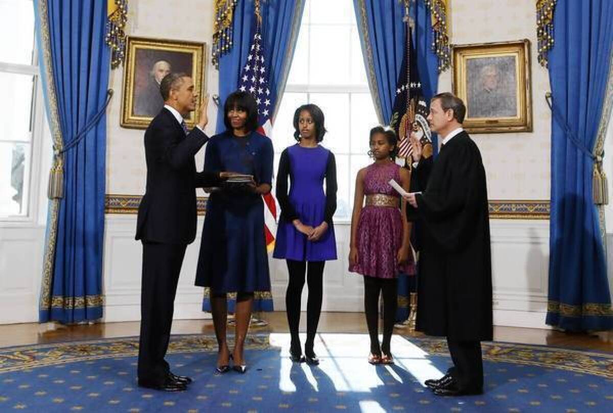 President Obama, with First Lady Michelle Obama and their children Malia and Sasha looking on, takes the oath of office. It was administered by Chief Justice John G. Roberts Jr.