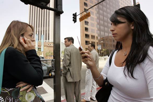 Tawny Murillo, right, and Veronica Ramirez try to call family and friends as they leave Archer Norris Law office located in the Wells Fargo building in the Bunker Hill area of downtown L.A. Officials urged people throughout Southern California to cut back telephone use because the system was being maxed out.